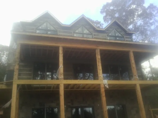 Dormers and porch framing on a large log home under construction — Roof Coating work by our crew in Palmer
